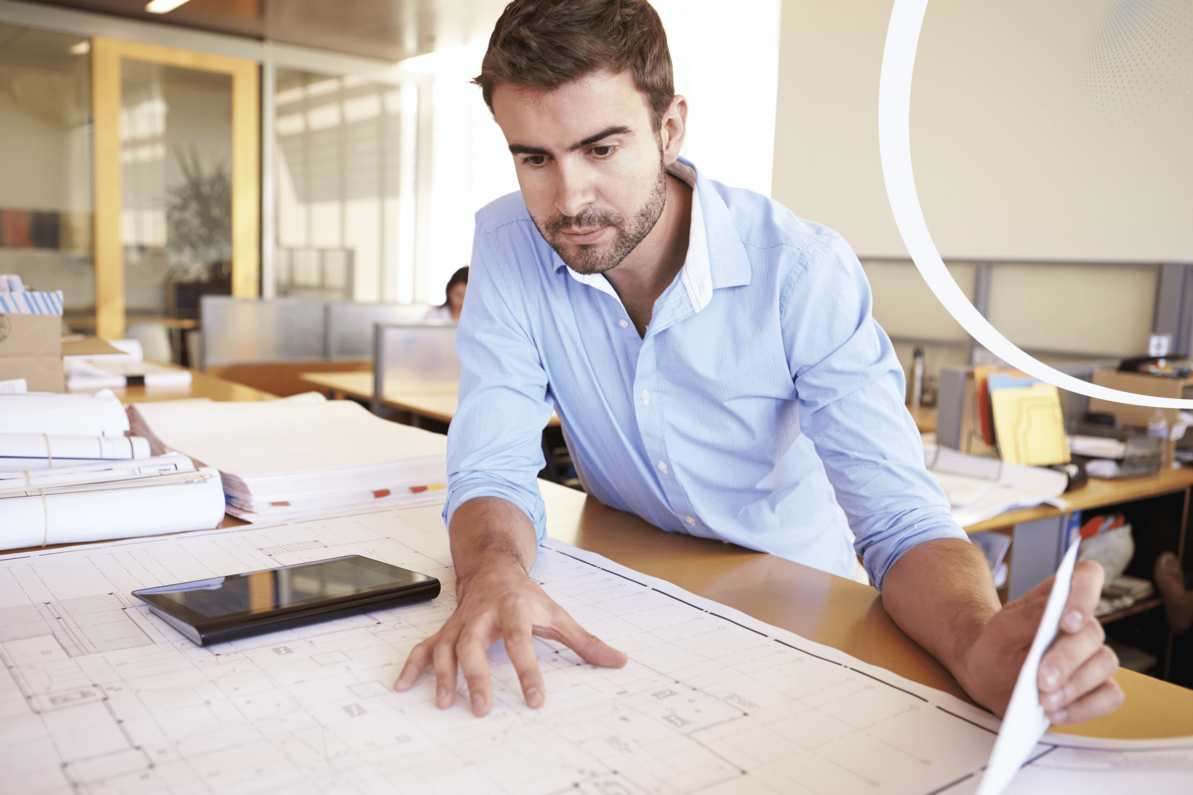 Male architect reviewing blueprints at desk