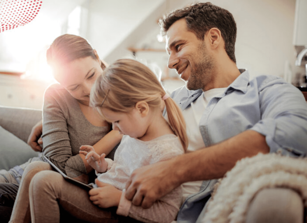Parents on sofa with child playing on tablet
